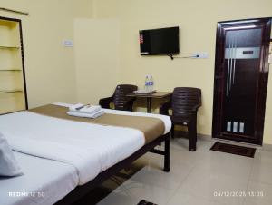 a bedroom with a bed and a desk and a tv at Rathore Inn in Hāora