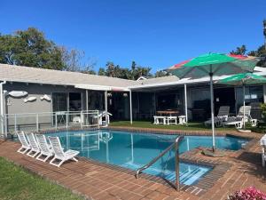 a house with a swimming pool with chairs and an umbrella at PrivateHolidayHome in Margate