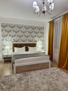 a bedroom with a large bed and a chandelier at Hotel Astoria in Astana