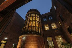 un edificio alto de ladrillo con una torre de reloj por la noche en The Hobson Cambridge by Adina, en Cambridge