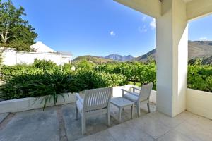 two chairs and a table on a patio with mountains at The Little Vineyard Cottage in Franschhoek