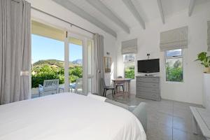 a bedroom with a bed and a tv and a balcony at The Little Vineyard Cottage in Franschhoek