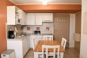 Beaune Levernois - Piscine Chauffée, Sauna et Golf في ليفيرنوا: مطبخ بخزائن بيضاء وطاولة خشبية