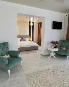 a bedroom with a bed and two chairs and a table at Complex Lebada Botosani in Botoşani