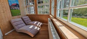 a room with a chair in a room with windows at Forsthaus Faistenau in Hintersee