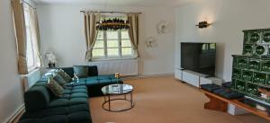 a living room with a couch and a tv at Forsthaus Faistenau in Hintersee
