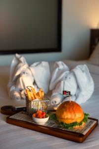 The Beach Residence Kata في شاطئ كاتا: صينية بها شطيرة وبطاطس مقلية على السرير