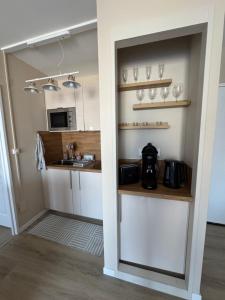 a kitchen with white cabinets and a sink at La parenthèse bleue, loggia et parking in Courseulles-sur-Mer +3 photos