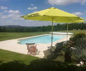 een zwembad met stoelen en een parasol ernaast bij Gite Laurélie, Un Écrin De Sérénité in Trémons