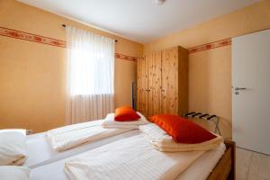een slaapkamer met twee bedden met oranje en witte kussens bij Casa Mia by K A M E L U in Gengenbach
