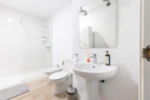 ein Badezimmer mit Waschbecken, Toilette und Spiegel in der Unterkunft Amati Boutique Coliving Madrid in Madrid
