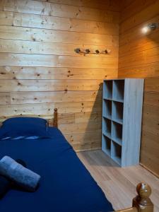 Schlafzimmer mit blauem Bett und Holzwänden in der Unterkunft La Ruche, Maison chaleureuse de 5 personnes in Aigueblanche