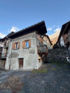 ein altes Steingebäude mit einem Balkon darauf in der Unterkunft La Ruche, Maison chaleureuse de 5 personnes in Aigueblanche