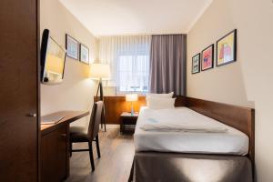a hotel room with a bed and a desk at Garner Hotel Friedrichshafen by IHG in Friedrichshafen +160 photos