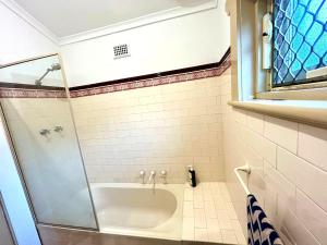 un baño con ducha y bañera en 3BR Guest House near Adelaide CBD Joslin 5070, en Evandale