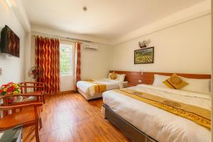 a bedroom with two beds and a desk and a window at Long Anh Hotel in Lao Cai