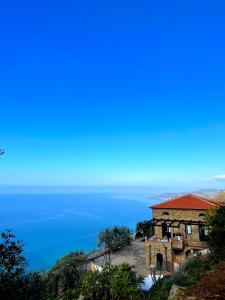 an old house on a hill with the ocean in the background at Casale Santa Rosalia Charme Villas and Rooms in San Mauro Cilento