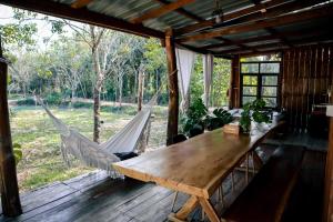 a wooden table and hammock on a screened in porch at Baanraipoonwana Baanboonmak in Ban Don Klang +7 photos