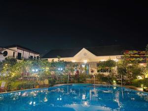 a large swimming pool in front of a building at night at Edu Home in Ba Vì