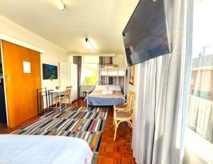 a room with a bedroom with a bed and a flat screen tv at Large quad guest room 6 with well-equipped kitchen in Highett