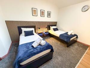 a bedroom with two beds and a clock on the wall at Core Citi Lets, Guild Street Rooms in Aberdeen