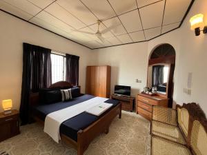 a bedroom with a bed and a desk and a television at RIVINSON Negombo in Negombo