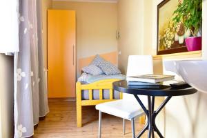 a small bedroom with a table and a yellow bed at Sobe - Rooms Stremljan Ljubljana in Medvode