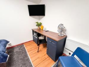 a room with a desk with a television on a wall at Core Citi Lets, Guild Street Rooms in Aberdeen