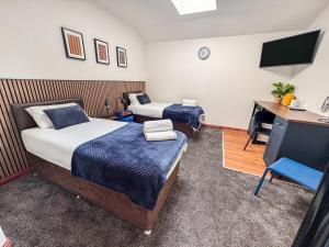 a room with two beds and a desk and a television at Core Citi Lets, Guild Street Rooms in Aberdeen