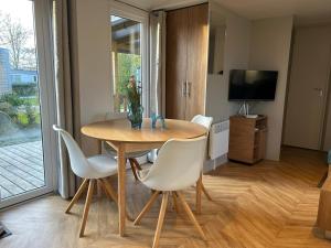 a dining room table with white chairs and a television at Chalet Aventura 1-6 pers- 3 slaapk- 2 badk- Berging- Inchecken al vanaf 13 uur - incl gebruik koffie en thee in Lauwersoog