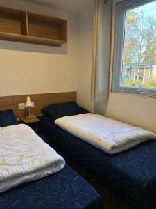 zwei Betten in einem Zimmer mit Fenster in der Unterkunft Chalet Aventura 1-6 pers- 3 slaapk- 2 badk- Berging- Inchecken al vanaf 13 uur - incl gebruik koffie en thee in Lauwersoog