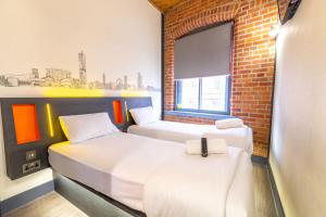 two beds in a room with a brick wall at easyHotel Manchester in Manchester