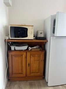 a microwave sitting on top of a wooden cabinet next to a refrigerator at Le Studio Louise Pratique & Central in Brides-les-Bains