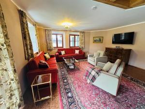 VILLA SEEBERG - by "Schloss Gessenberg" luxurious vacation home with lake and mountain views, suitable for families and friends في Petting: غرفة معيشة مع أرائك حمراء وتلفزيون