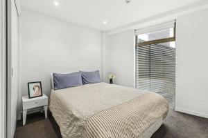 a white bedroom with a bed and a window at 3-Bedroom CBD Elevate Apartment in Wellington