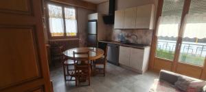 a kitchen with a table and chairs and a table and a kitchen with windows at Maison au coeur du Jura - 4 chambres - 9 couchages in Champagnole