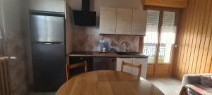 a kitchen with a wooden table and a refrigerator at Maison au coeur du Jura - 4 chambres - 9 couchages in Champagnole +10 photos