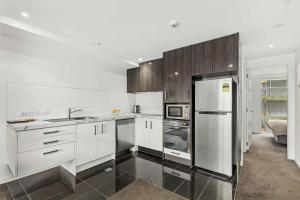a kitchen with white cabinets and a stainless steel refrigerator at 3-Bedroom CBD Elevate Apartment in Wellington