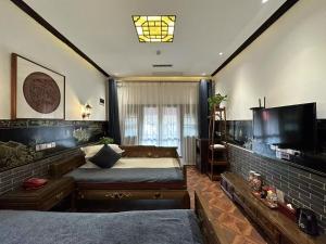 Un dormitorio con una cama grande y un televisor. en Pingyao Grand Theater Guild Hall East Garden, en Pingyao