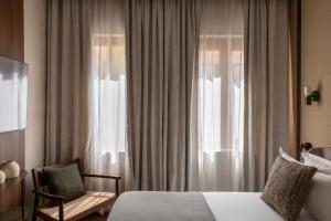 a bedroom with a bed and a chair and a window at NAMAN HOTELLERIE - Roma in Rome +19 photos