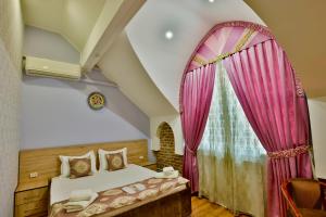 una camera con letto e finestra con tende rosa di AaSia a Bukhara