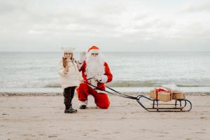 a woman is pulling a santa claus sleigh on the beach at Hotel Linea Mare in Pobierowo