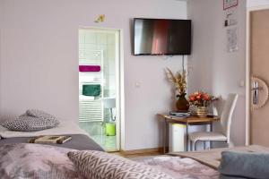 a bedroom with two beds and a table and a television on the wall at Sobe - Rooms Stremljan Ljubljana in Medvode