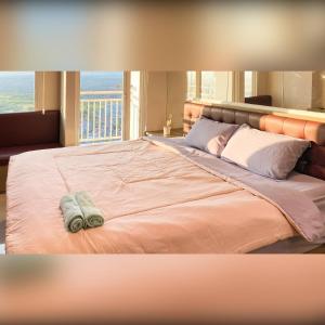 a bedroom with a large bed with a large window at Tanglin Tower with Netfix by AquHome in Surabaya
