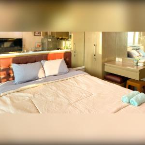 a bedroom with a large bed and a kitchen at Tanglin Tower with Netfix by AquHome in Surabaya +4 photos