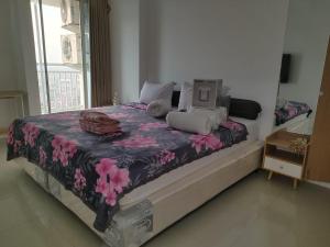 a bedroom with a bed with a floral bedspread at Tanglin Tower with Netfix by AquHome in Surabaya