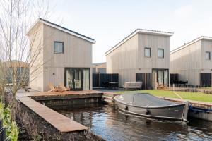 un barco en el agua frente a una casa en Waterlodge in Heeg - Relax, sail and enjoy!, en Heeg