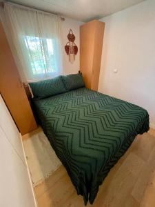 a green bed in a room with a window at Nómada-Casa con Jacuzzi, Cerca de Sevilla in Alcalá de Guadaira