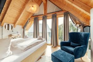 a bedroom with a large bed and a blue chair at Rehfugium Lachtal by ALPS RESORTS in Lachtal