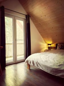 a bedroom with a bed and a large window at Domek w Poleskim Parku in Urszulin